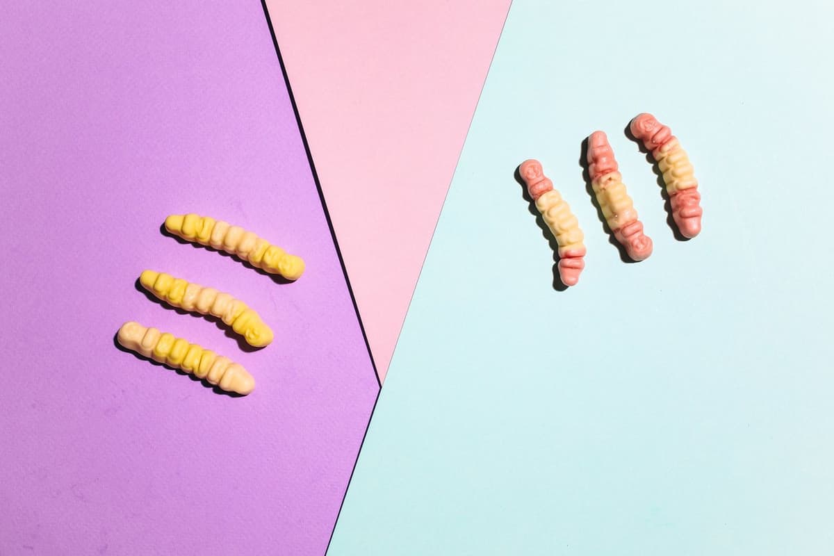 A playful arrangement of gummy worms on colorful paper backgrounds, perfect for sweets imagery.