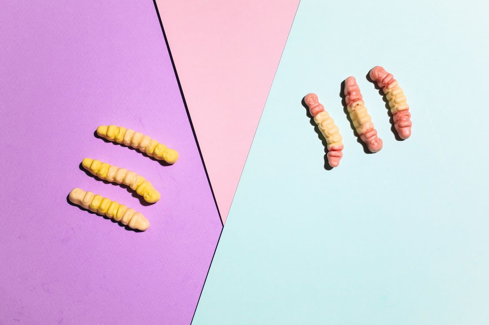 A playful arrangement of gummy worms on colorful paper backgrounds, perfect for sweets imagery.